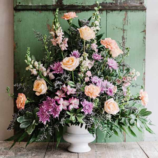 Pastel floral arrangement in a white pedestal vase