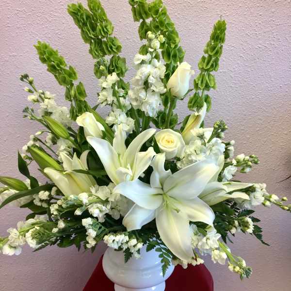 White lilies and roses in a white vase with tall green spikes