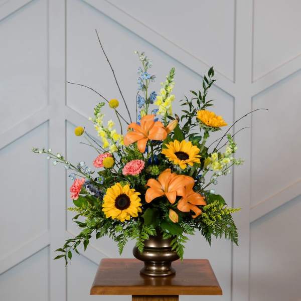 Colorful floral arrangement in a bronze vase with sunflowers and lilies
