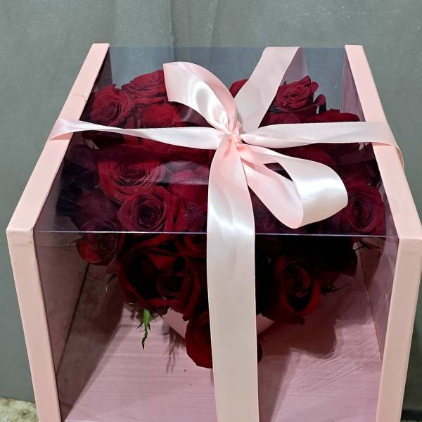 Boxed bouquet of deep red roses tied with a pale pink ribbon