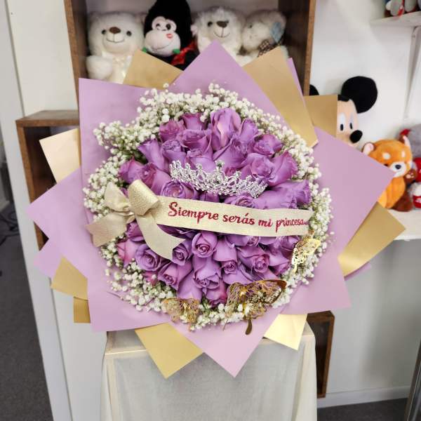 Purple rose bouquet with a tiara and ribbon reading "Siempre serías mi princesa"