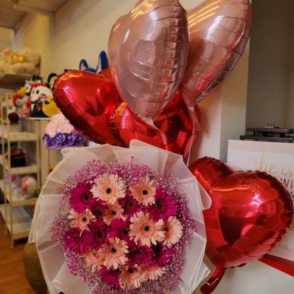 Pink gerbera bouquet with red and rose-gold heart balloons