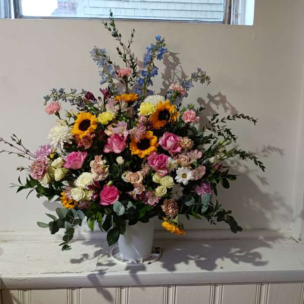 Large mixed bouquet in a white vase with pink, yellow, and blue flowers