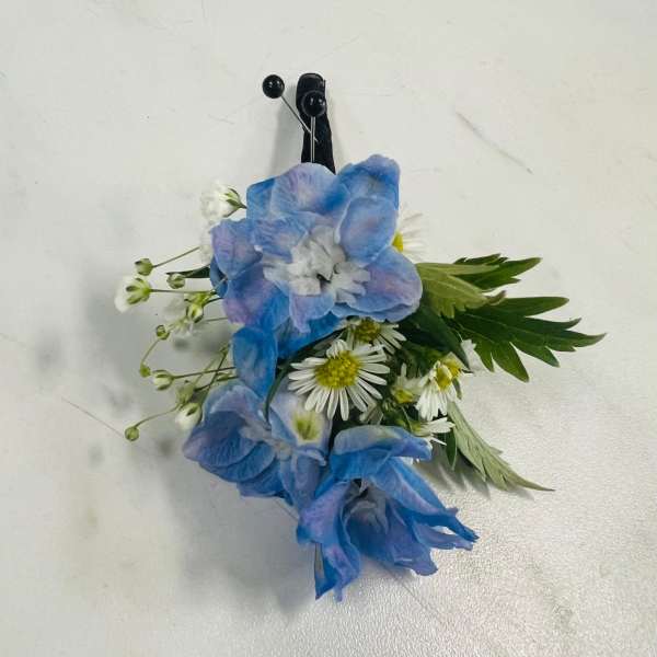 Blue and white floral boutonniere with a black pin