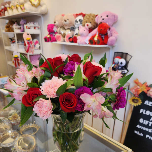 Bouquet of red roses, pink alstroemeria, and carnations in a clear glass vase