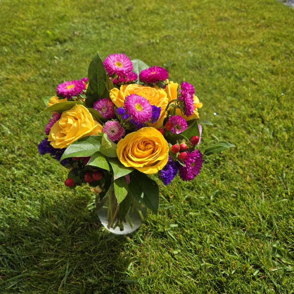 Bouquet of yellow roses and pink daisies in a glass vase