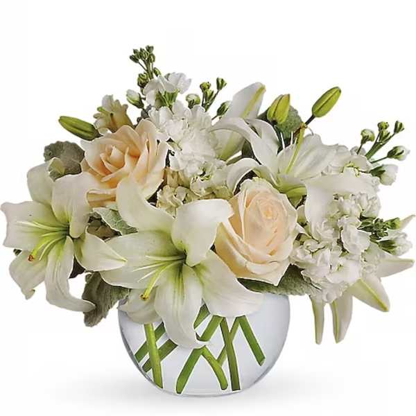 White lilies and pale roses arranged in a clear glass vase