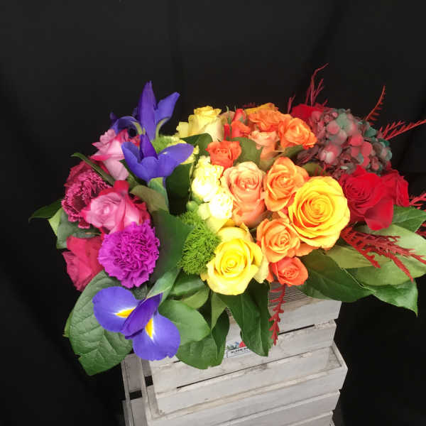 Colorful bouquet of roses and irises in a white crate