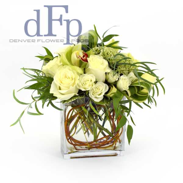 White roses and green orchids in a square glass vase