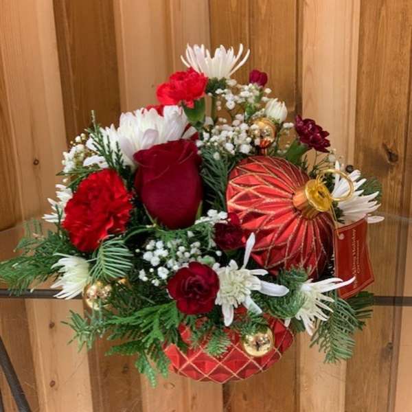 Red and white floral arrangement with ornaments in a decorative container