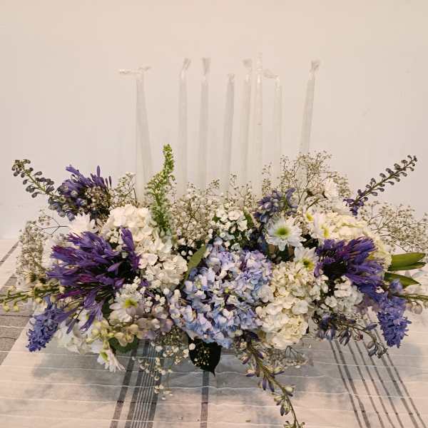 Low floral centerpiece with white and purple flowers on a table