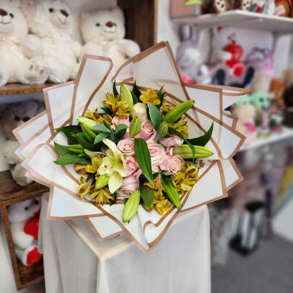 Bouquet of pink roses and yellow lilies wrapped in white paper