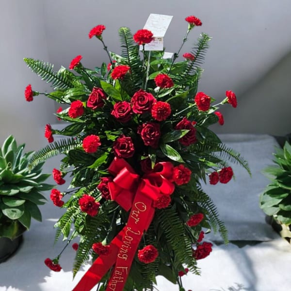 Standing red rose and carnation spray with a red ribbon