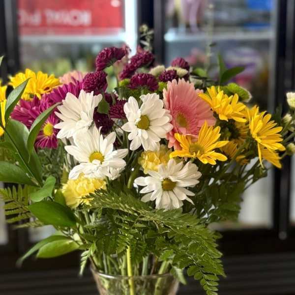 Mixed bouquet of daisies and chrysanthemums in a clear glass vase