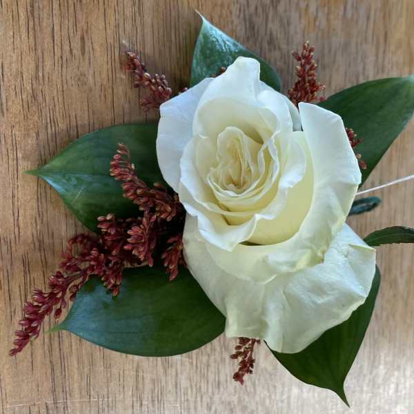 White rose boutonniere with dark green leaves and red filler flowers
