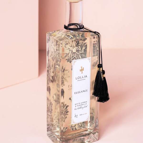Clear glass bottle with gold cap and black tassel label