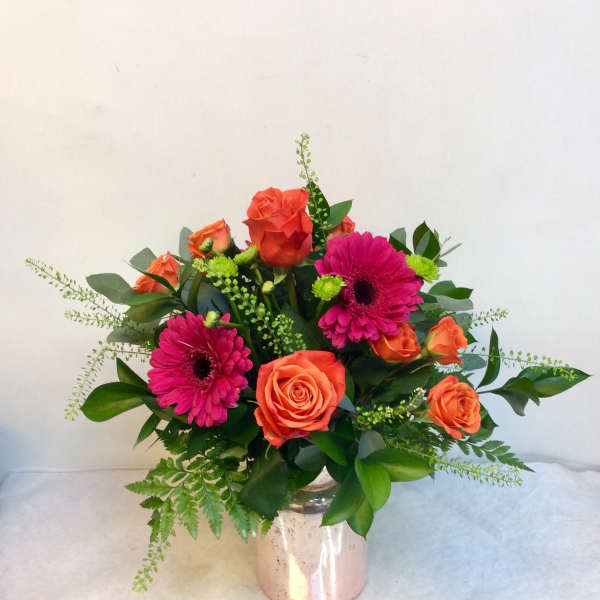 Bouquet of orange roses and pink gerbera daisies in a metallic vase