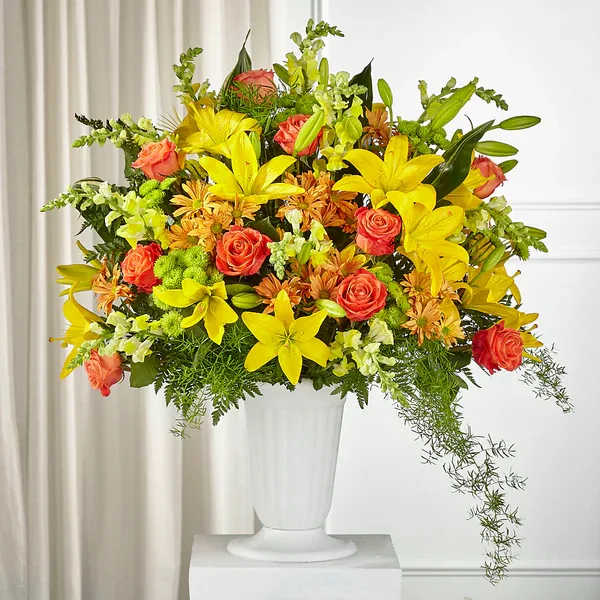 Bright mixed bouquet of yellow lilies and orange roses in a white vase
