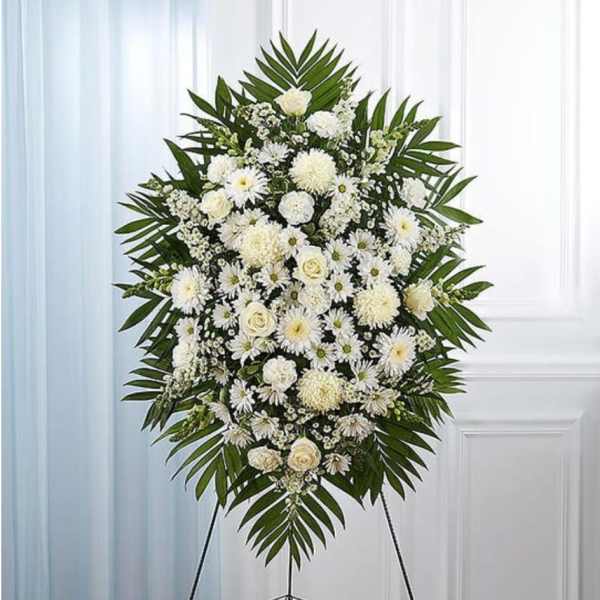 White floral standing spray with palm fronds on an easel