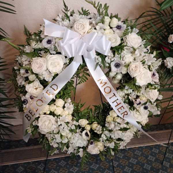 White floral funeral wreath with a satin bow and ribbon