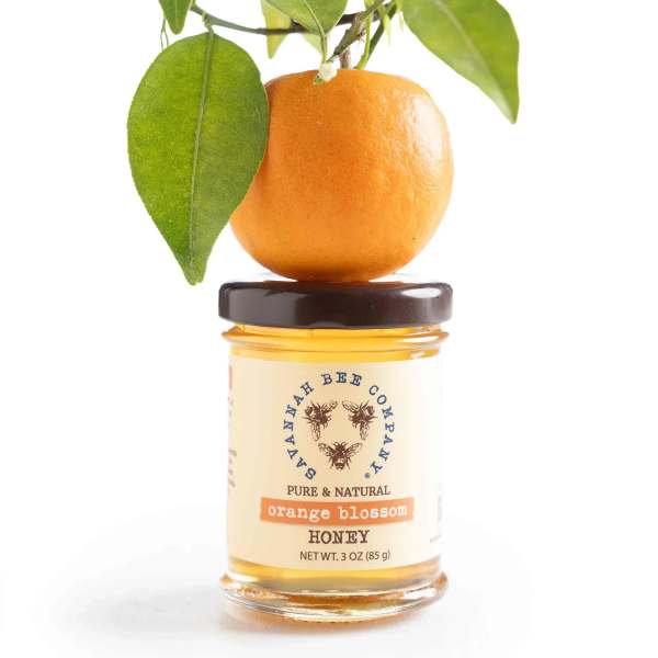 Orange blossom honey jar topped with an orange and leafy branch