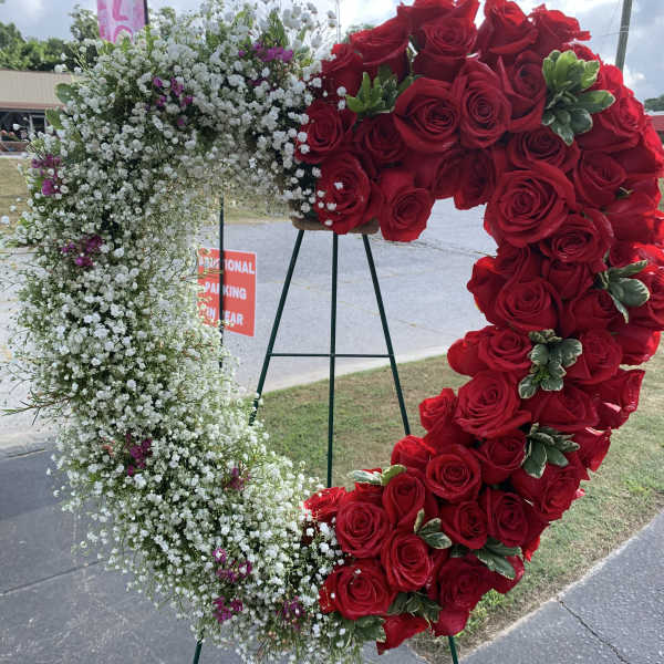 Heart-shaped floral wreath with red roses and white baby's breath on an easel