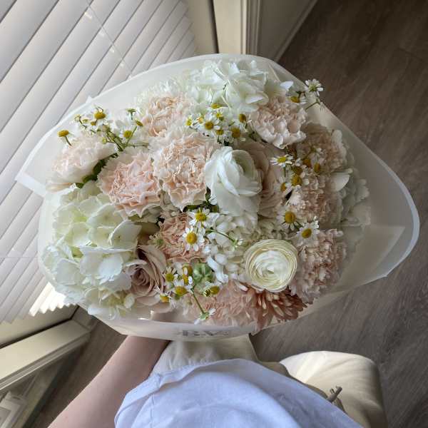 Bouquet of pale pink and white flowers wrapped in white paper