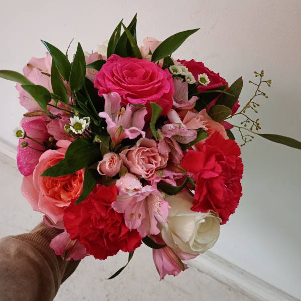 Handheld bouquet of pink and red roses with carnations and white blooms