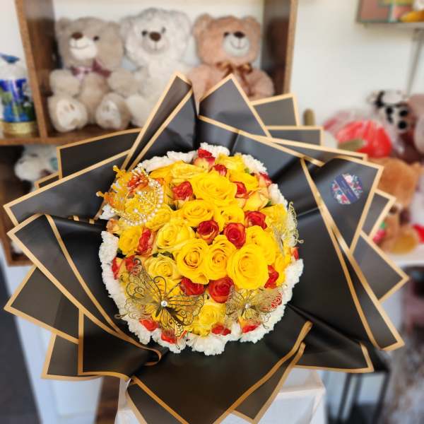 Bouquet of yellow and red roses wrapped in black paper