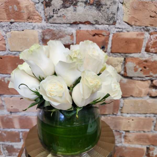 White roses arranged in a green glass vase
