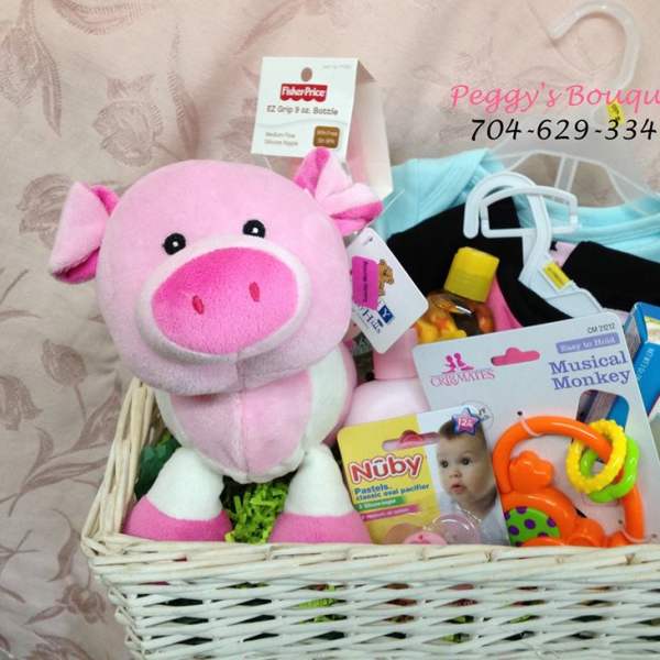 Gift basket with a pink plush pig, baby clothes, pacifier, and baby care items