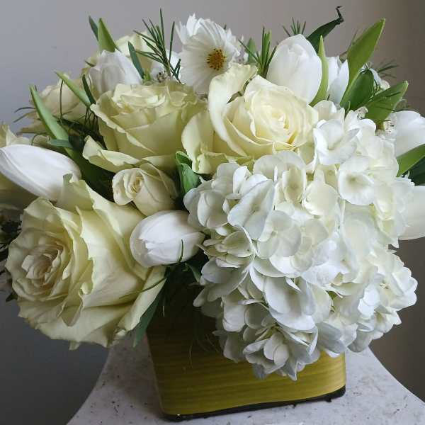 White roses and hydrangeas arranged in a yellow vase