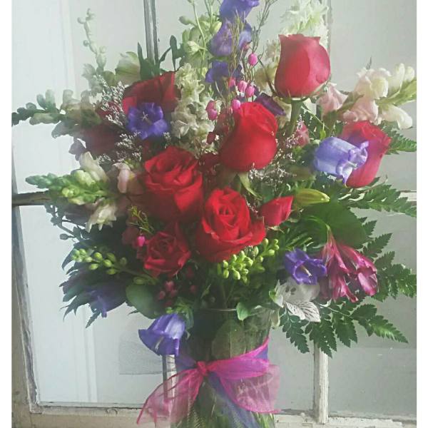 Bouquet of red roses and purple flowers in a glass vase