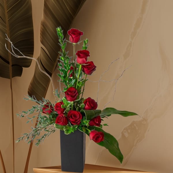 Tall arrangement of red roses in a black vase