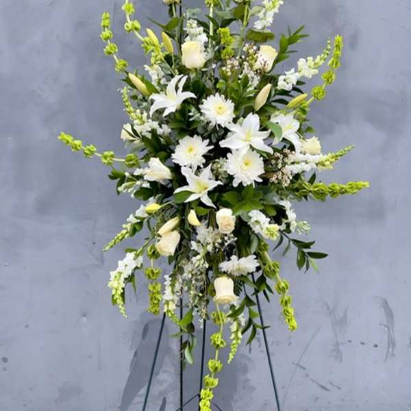 Tall white floral spray on a stand with green accents