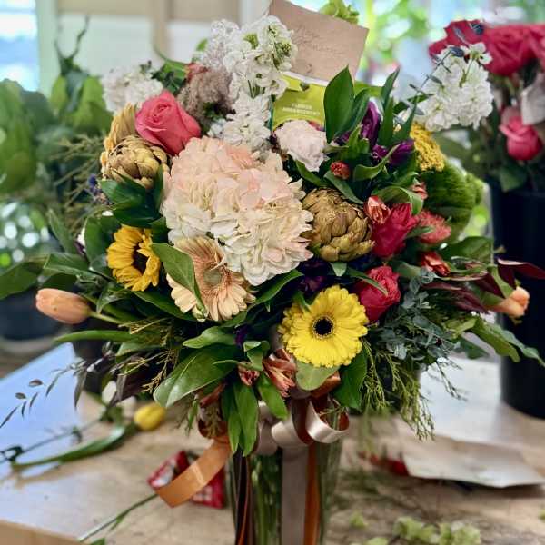 Mixed bouquet with pink, white, and yellow flowers in a glass vase