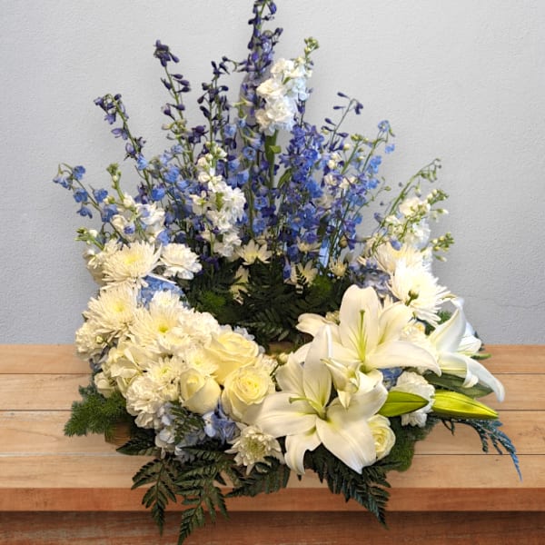 White lilies and blue flowers in a low floral arrangement