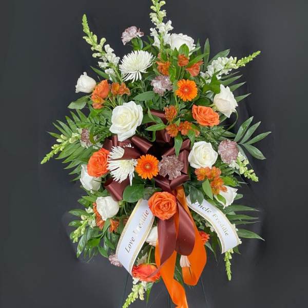 Standing floral spray with white and orange blooms and ribbon accents