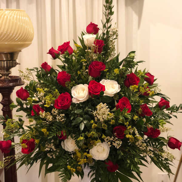 Large arrangement of red and white roses in a pedestal vase