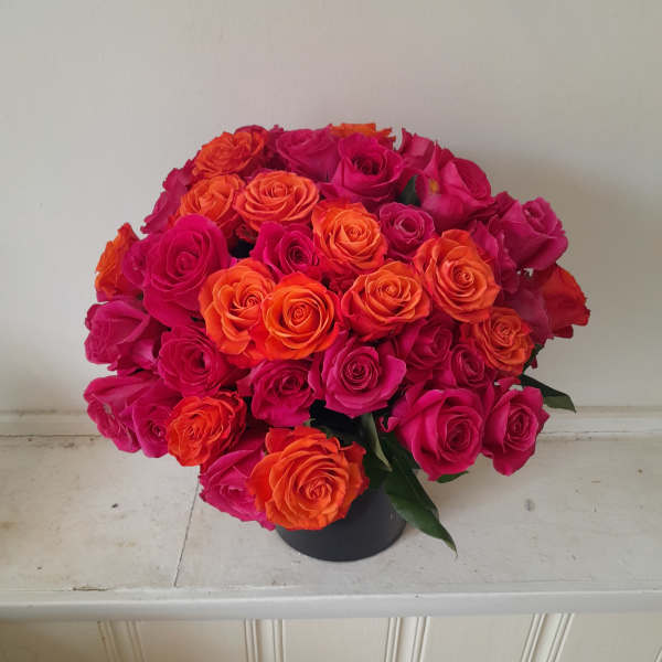 Bouquet of hot pink and orange roses in a black container