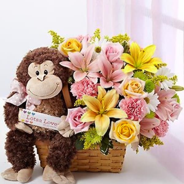 Stuffed monkey beside a basket of pink and yellow flowers