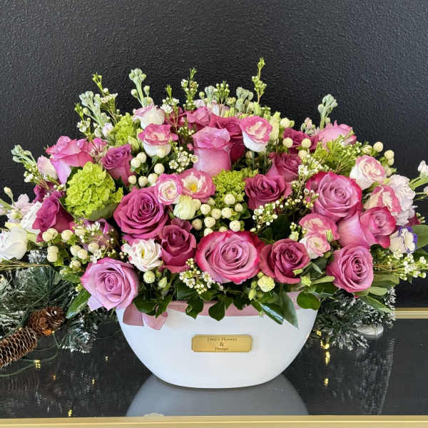 Pink and lavender rose arrangement in a white container