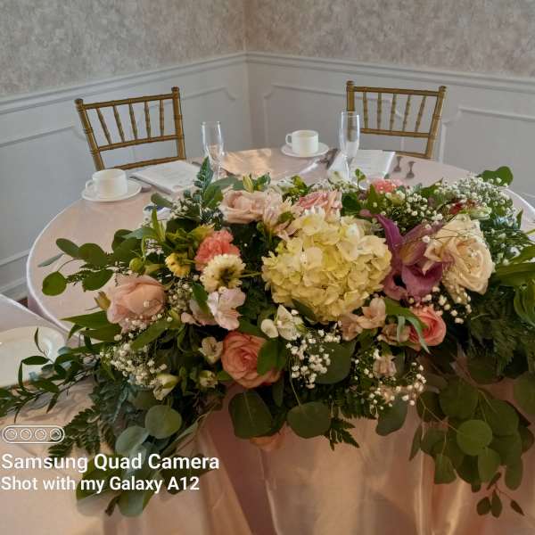 Large floral centerpiece with pink and cream flowers on a round table