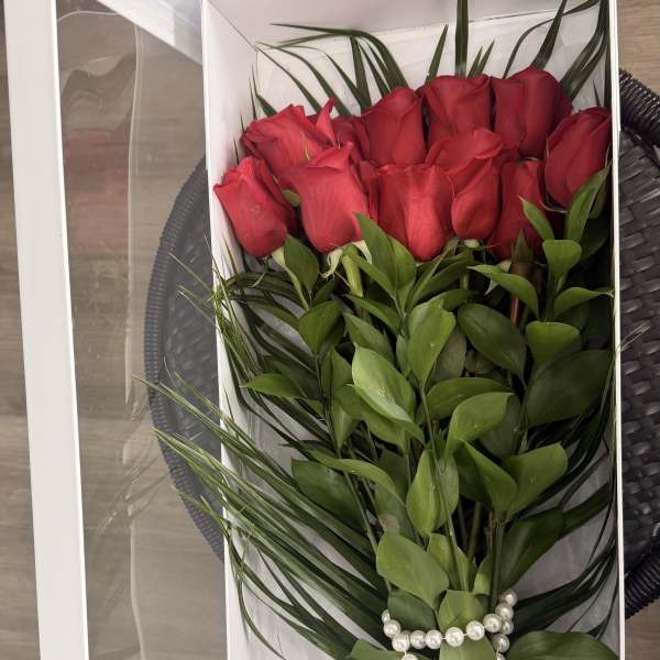 Red roses arranged in a white gift box with pearl accents