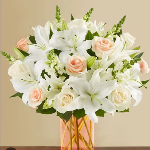 White lilies and pale peach roses in a glass vase