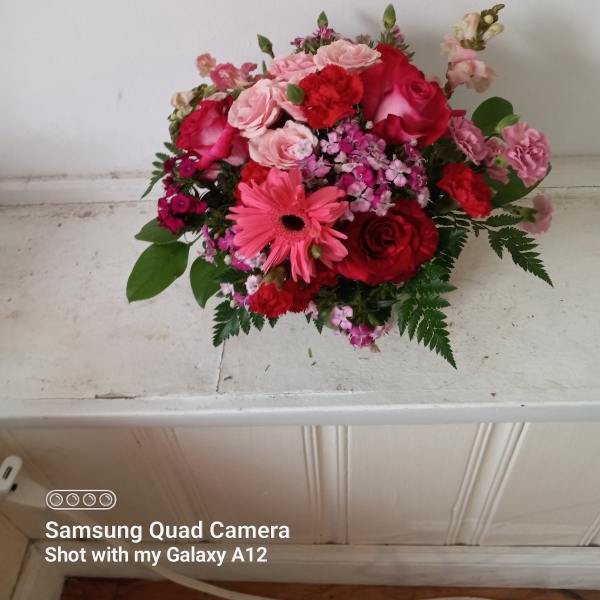 Pink and red mixed flower bouquet on a white surface