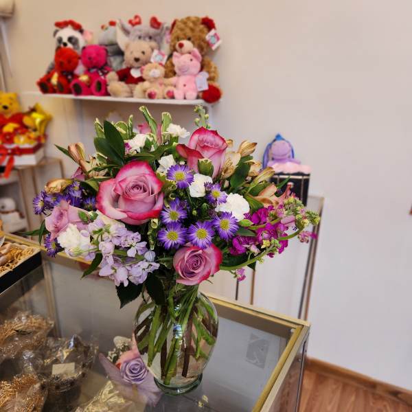 Mixed bouquet of pink roses and purple daisies in a glass vase