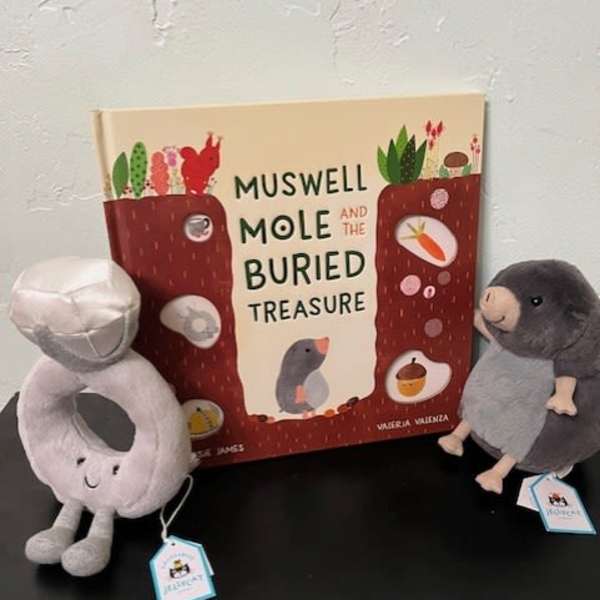 Two plush moles beside a children's book on a table