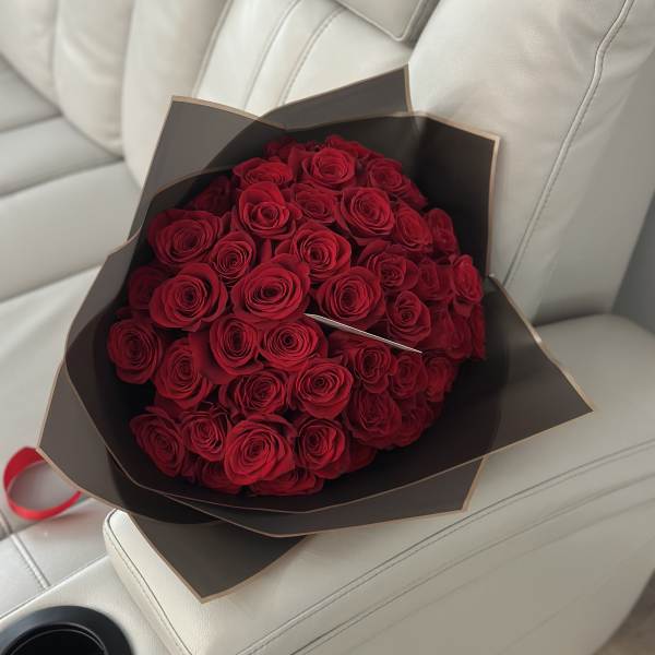 Bouquet of red roses wrapped in dark paper