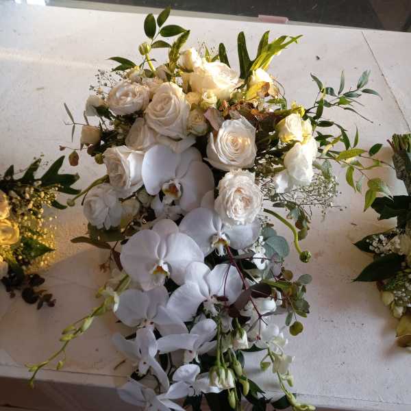 White rose and orchid bouquet with trailing greenery